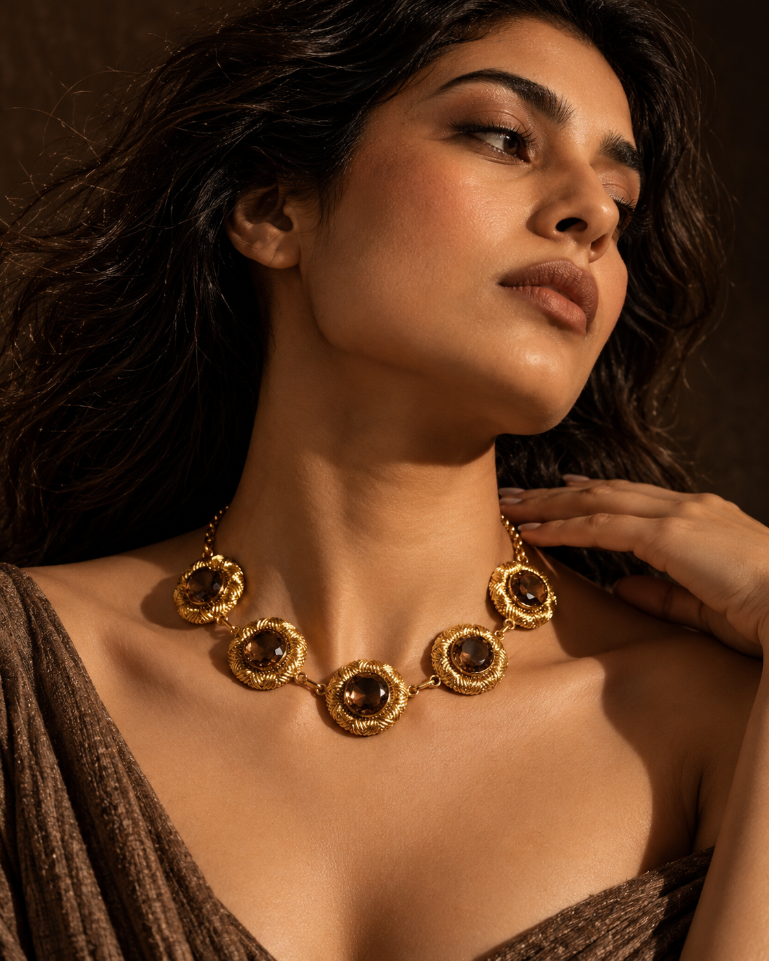 Medoso Jewellery gold statement necklace with textured circular medallions and dark brown gemstones, worn by a model in a cinematic luxury jewellery editorial.