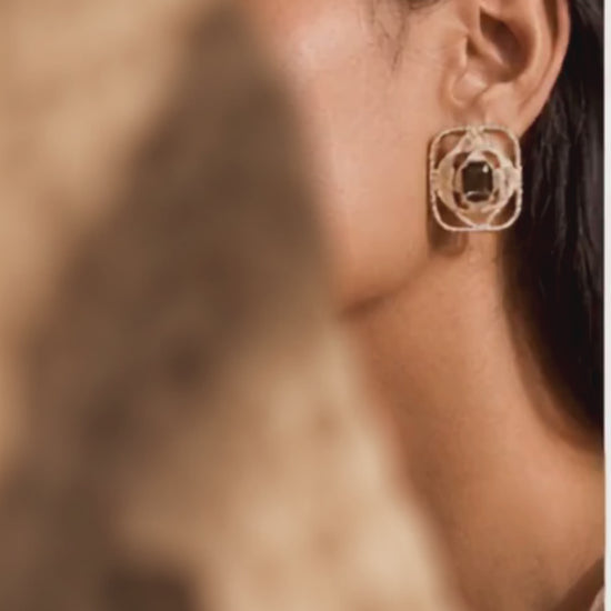 Luxury statement gold earrings with pavé texture and a central smoky gemstone, photographed on a woman in an elegant jewellery editorial.