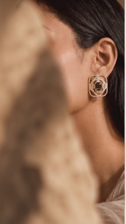Luxury statement gold earrings with pavé texture and a central smoky gemstone, photographed on a woman in an elegant jewellery editorial.